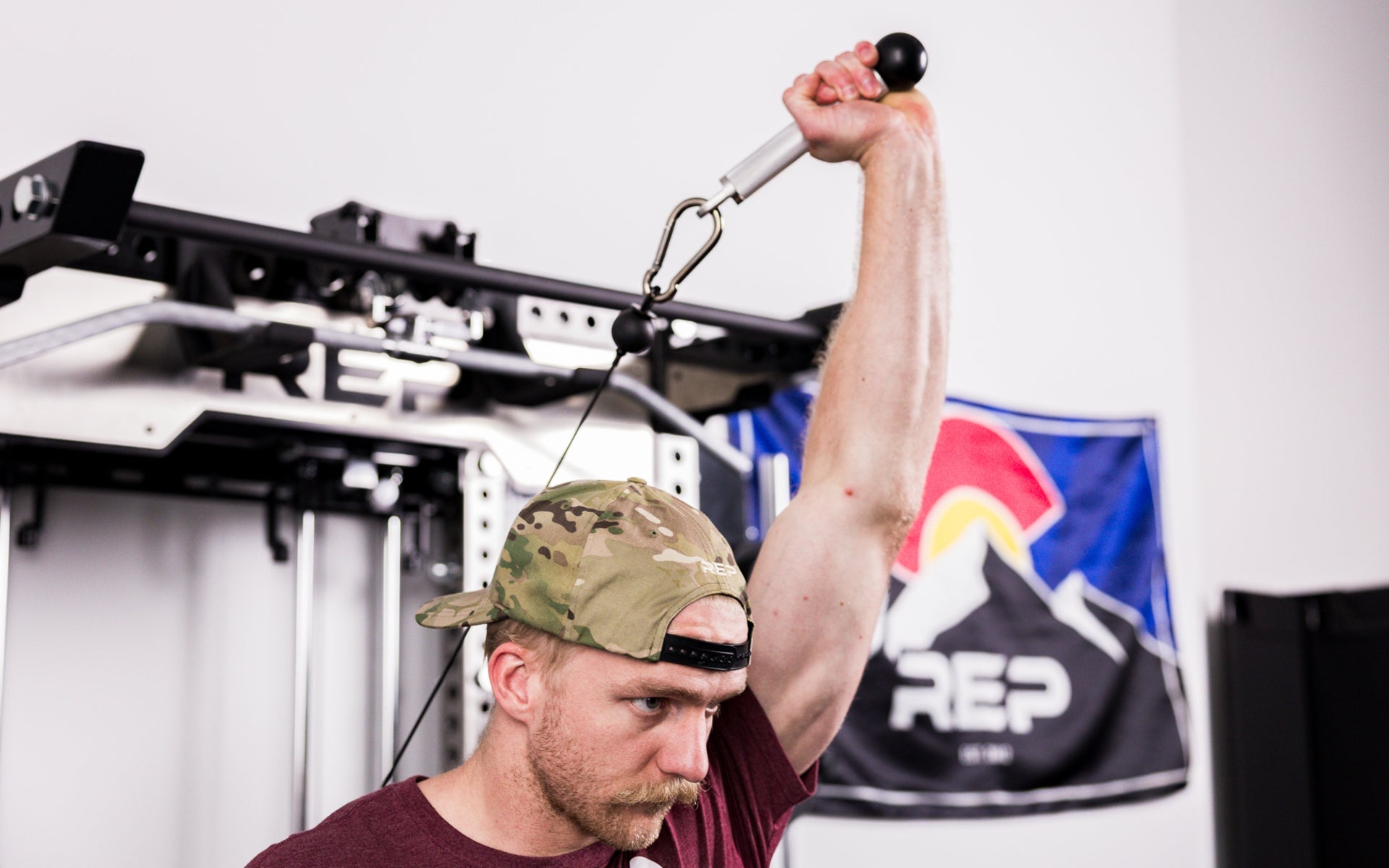 An athlete using the REP® x Kleva Built® ISO Pushdown Grip Cable Attachment to perform overhead tricep extensions